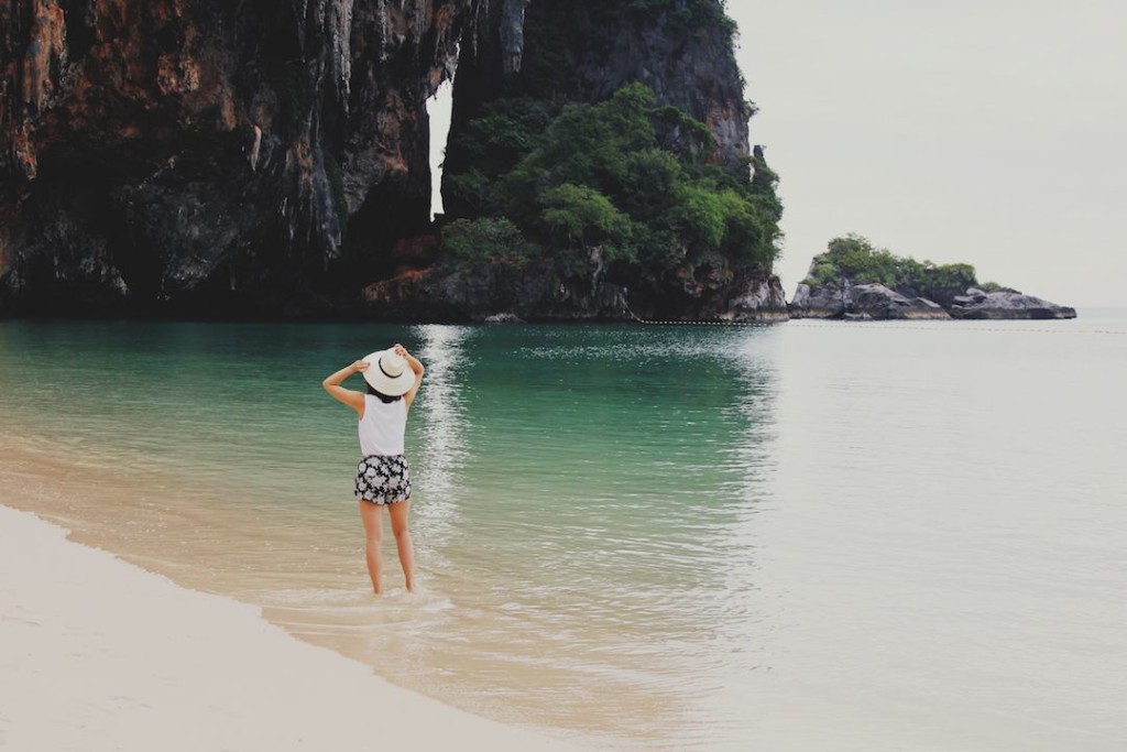 chic girl stands in the shallows of a beach