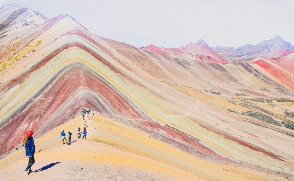 people walking on a mountains with rainbow like colours during daytime photography