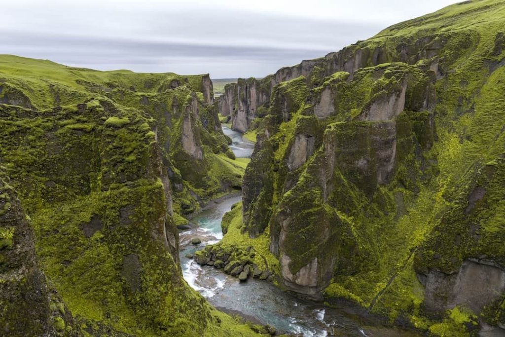 Flowing water cuts through a canyon covered in green grass