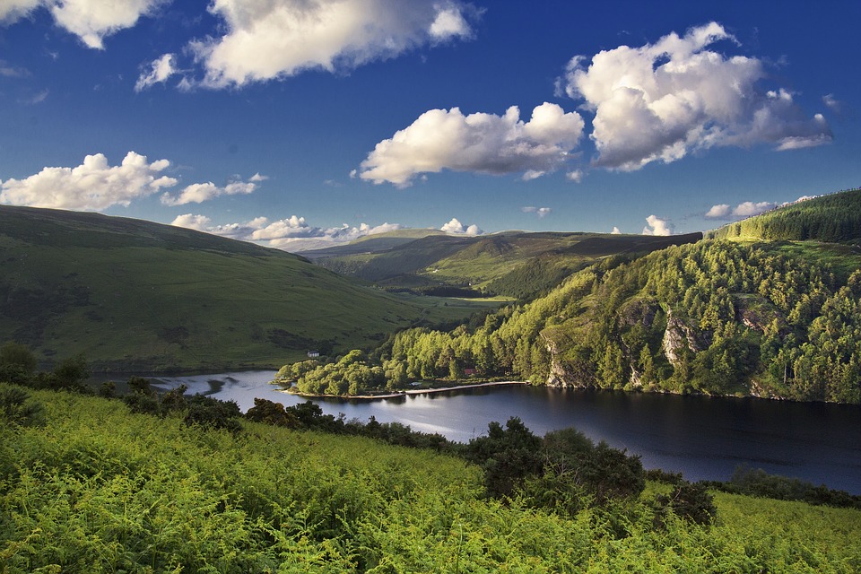 a blue lake between rolling hills and green pastures