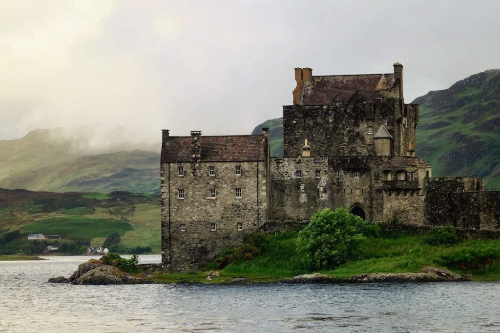 An old Scottish castle in the green countryside alongside a waterbody