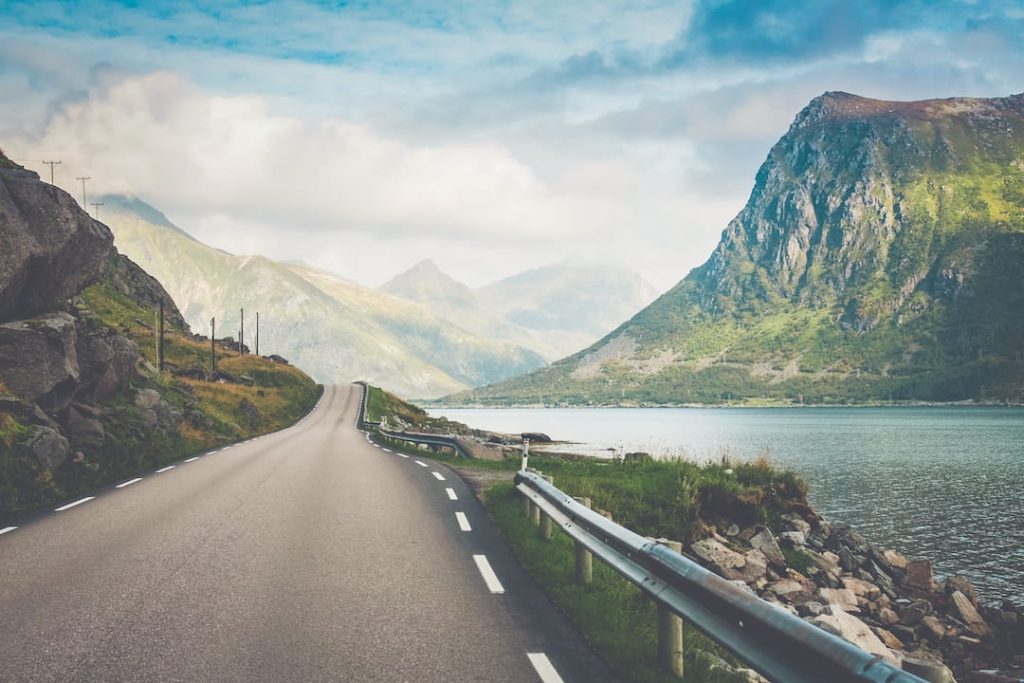 A stunning highway through Norway's green scenery alongside a lake