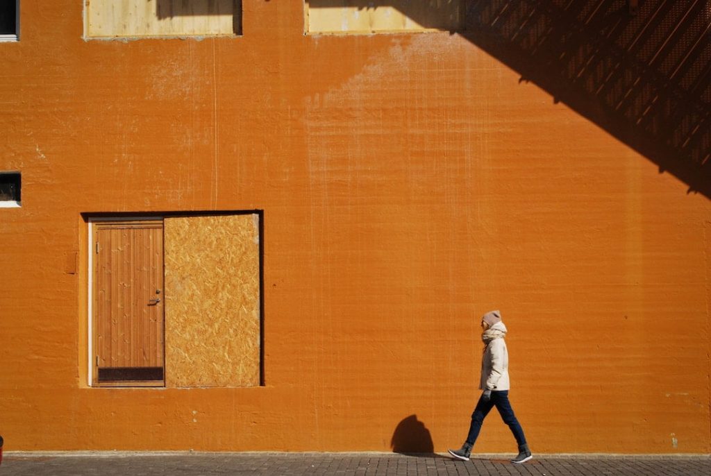 A woman walks by a bright orange wall in norway 