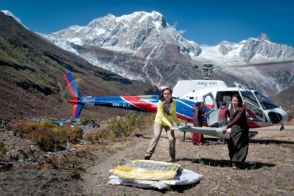 two woman unload relief supplies from a helicopter on Everest