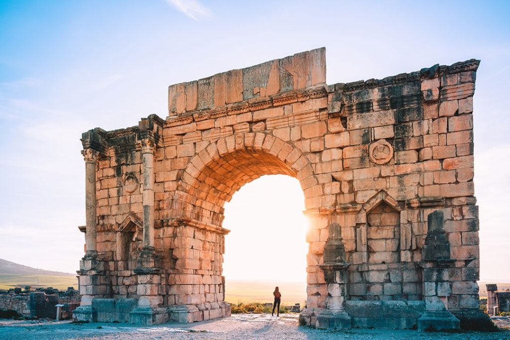 Sun peaks through a stunning arch in Volubilis of Morocco