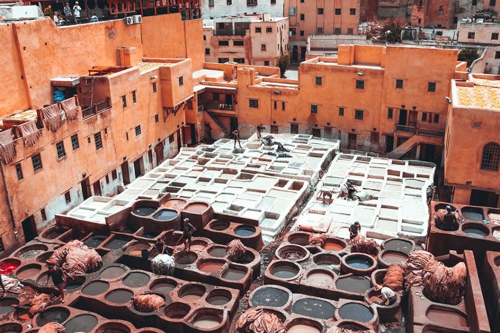 Workers in a tannery go about tanning and dying massive pieces of leather