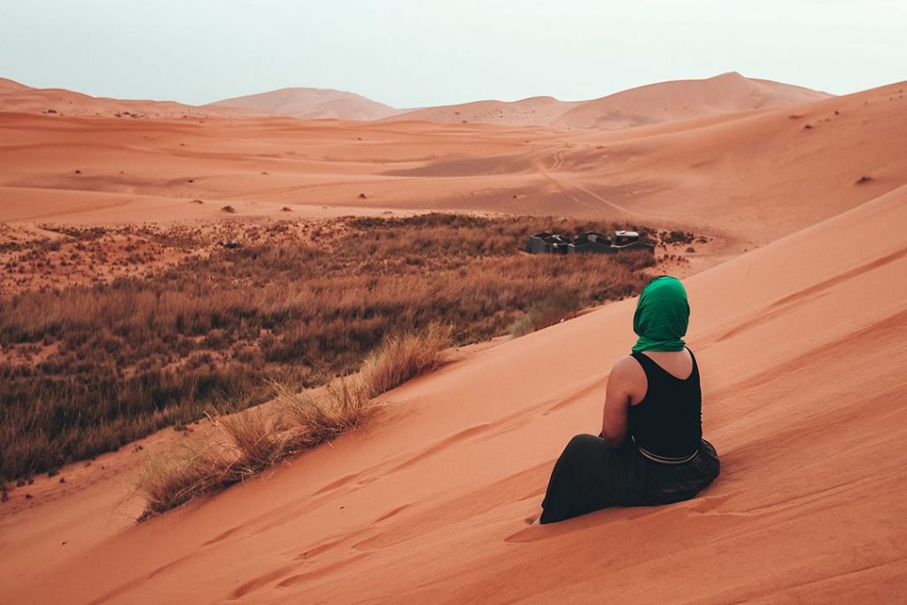 A traveller gazes out at the unending sandy landscape of Sahara Camp