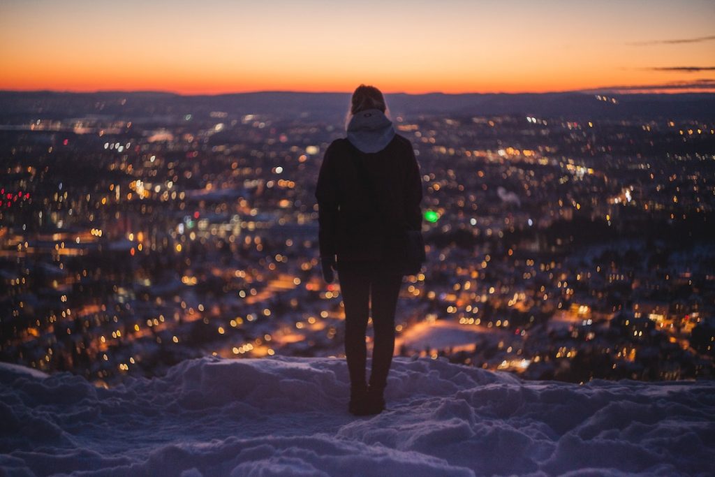 Woman standing above Oslo, Norway at night