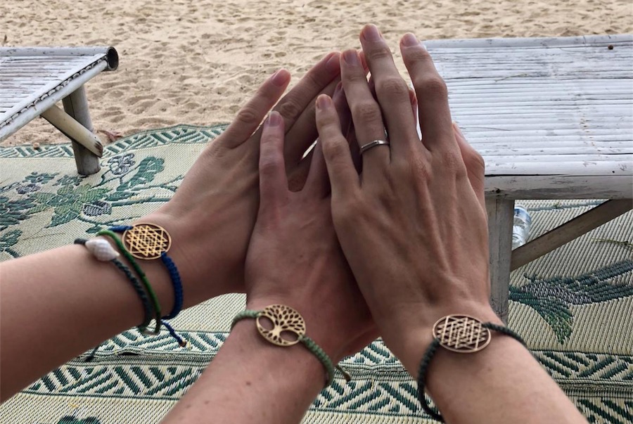 Three girls hold up their breath bracelets to the screens