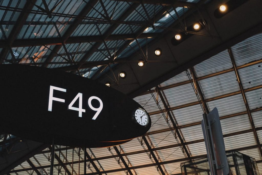 An ovular airport gate that reads "F49" in an airport at sunrise