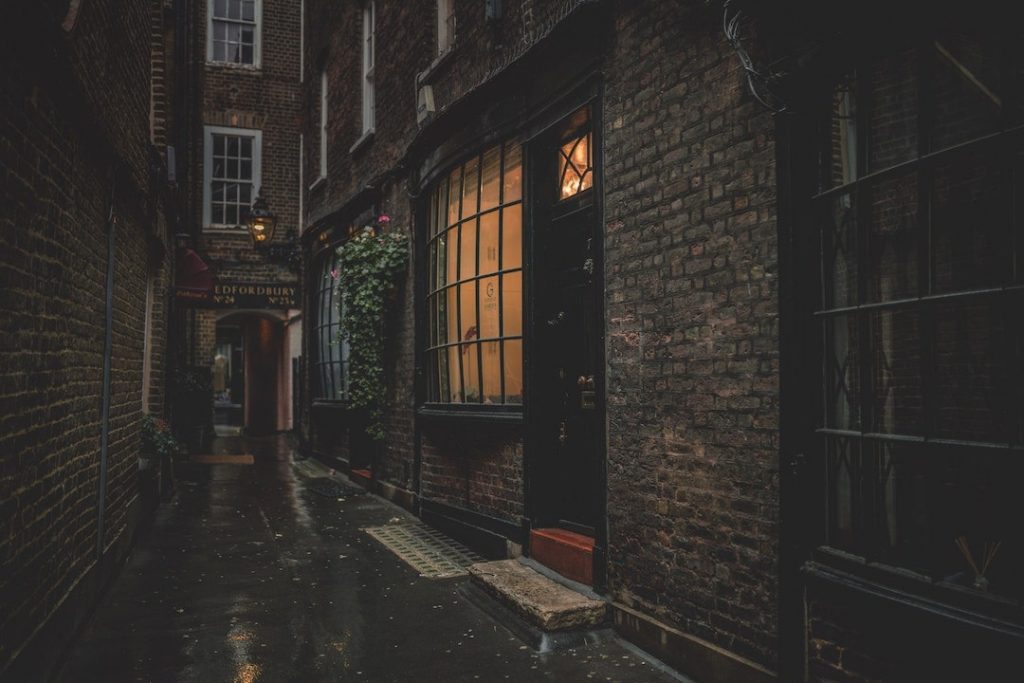 a dark alley in London with a light on in one window