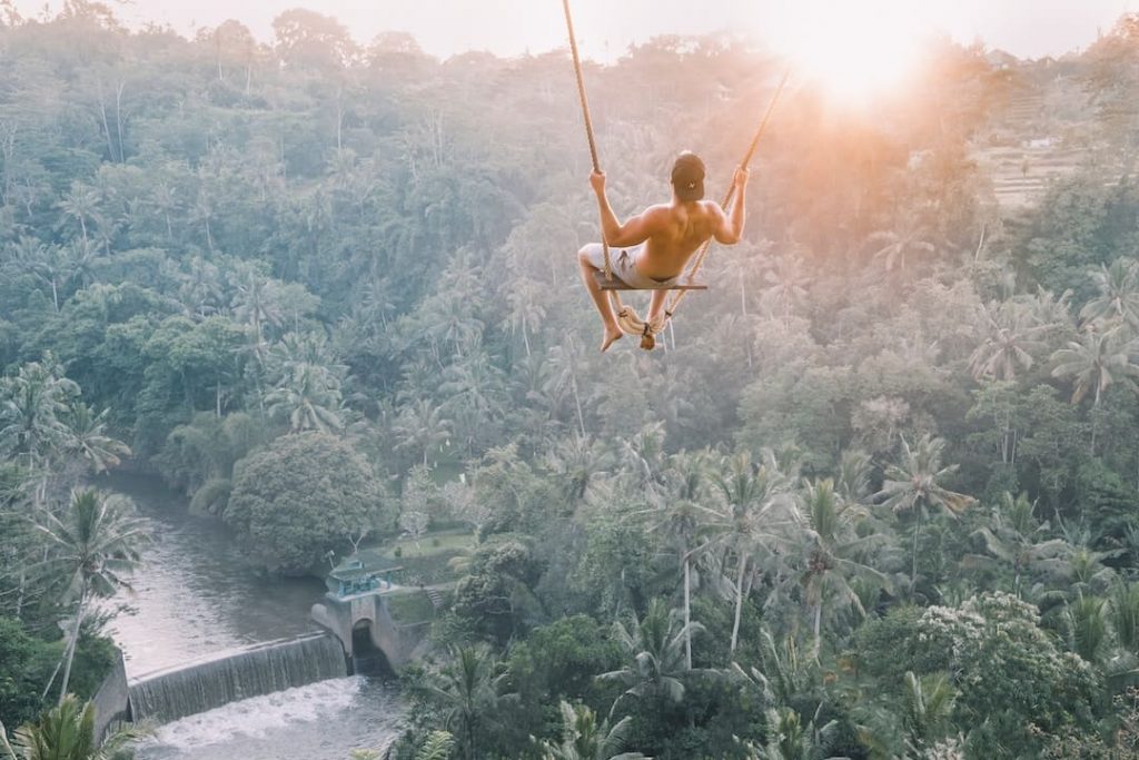 A man on a swing above the forest in Bali