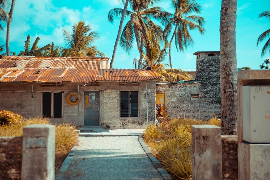 an abandoned house with a red roof on a sunny day in the Maldives