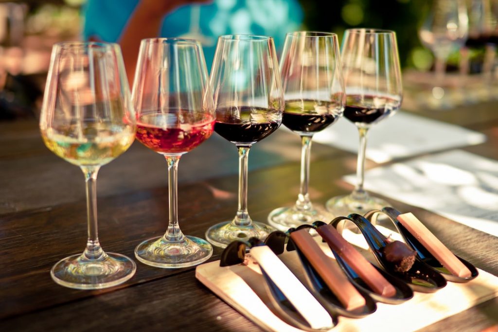 five glasses of wine, ranging from white to red, lined up for a tasting