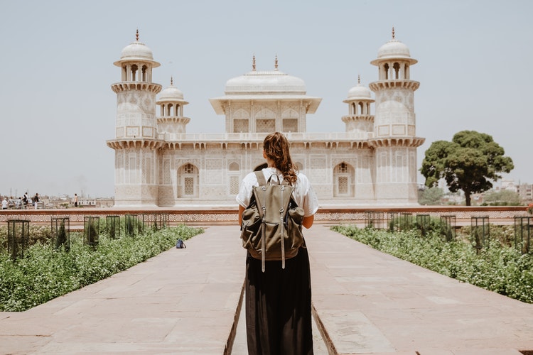 a girl with a back pack stands in front of a Tomb of I'timād-ud-Daulah in Agra India