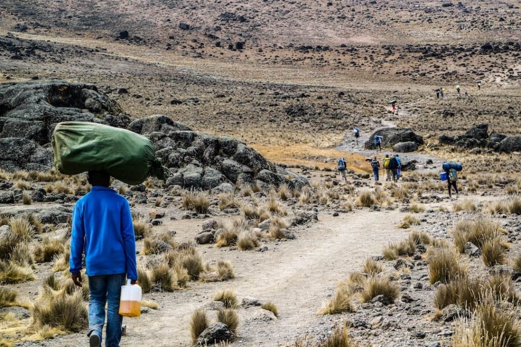 A guide balancing a bag on his head on Mount Kilimanjaro, Tanzania