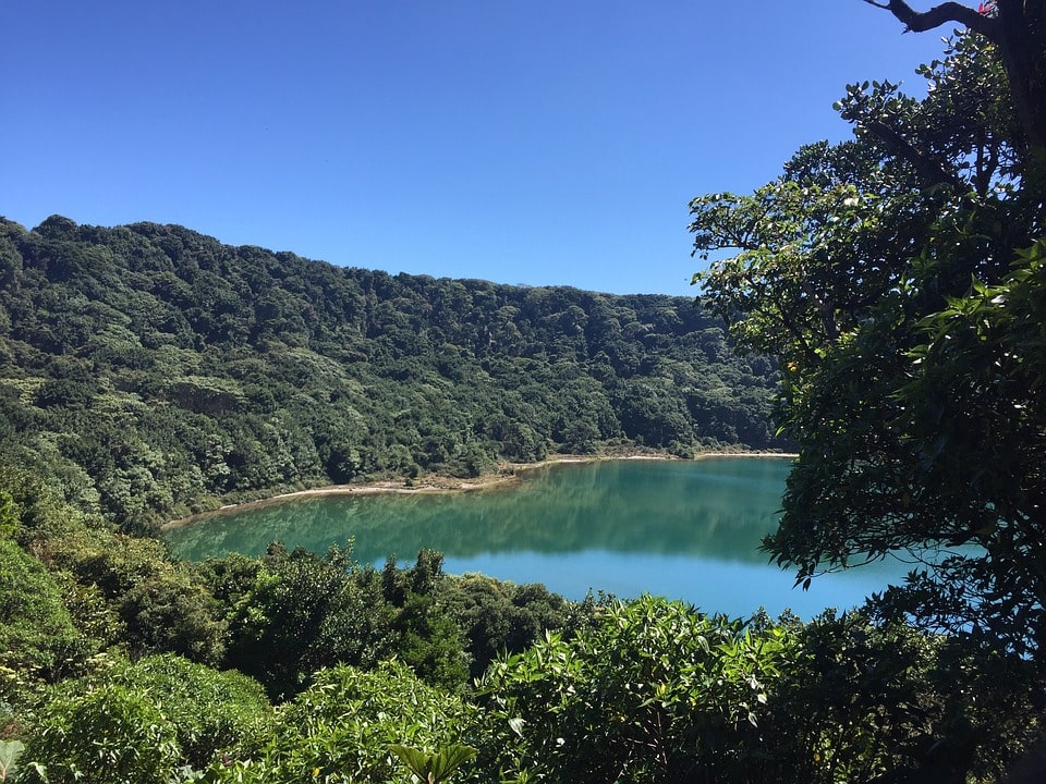 The deep Poas Volcano Crater filled with aquamarine water surrounded by lush foliage