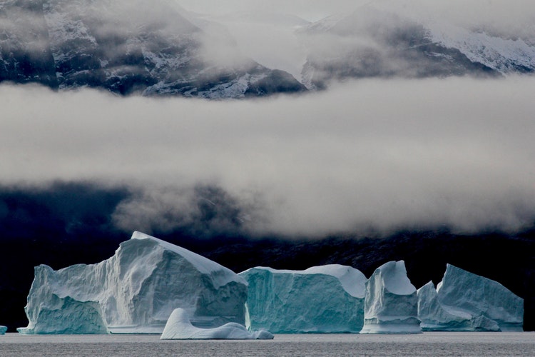 An iceberg in Greenland sits below the mist