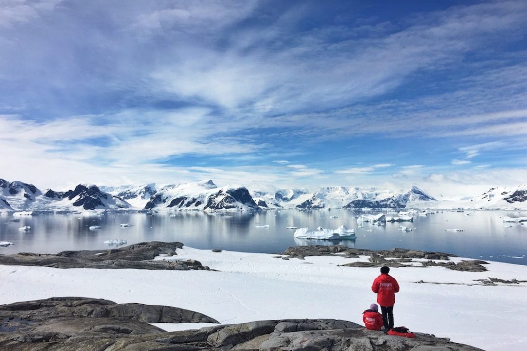 Two people stand on the edge of Antarctica