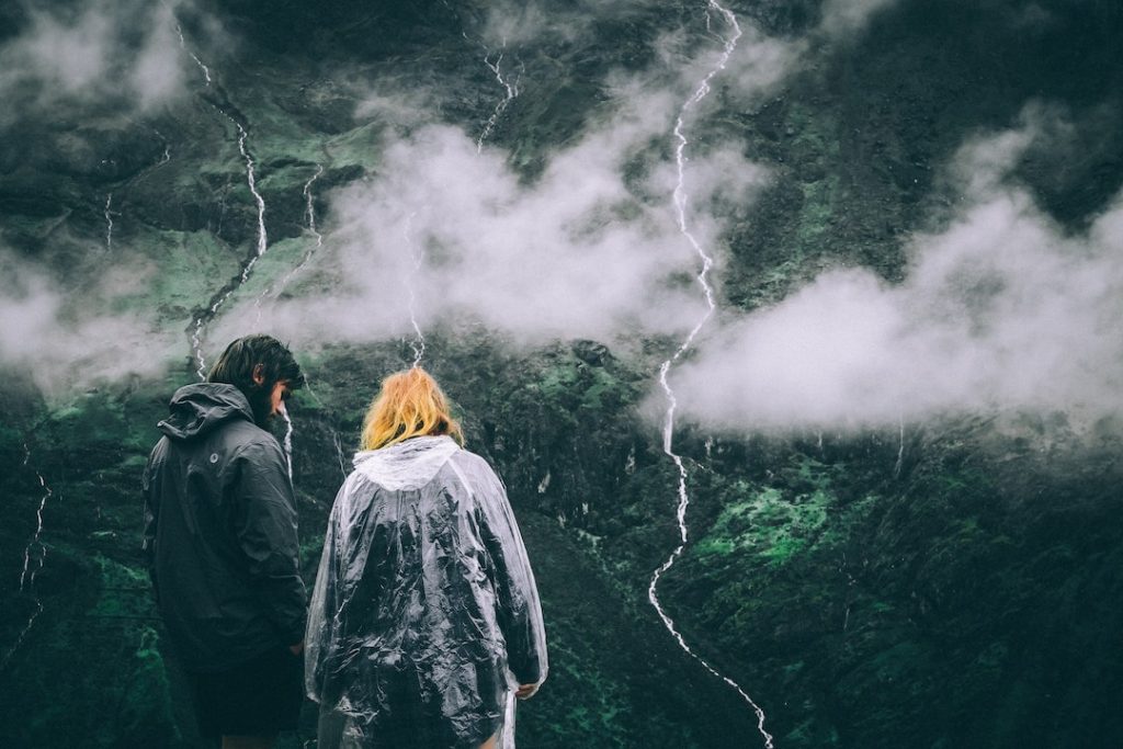 Two people overlooking foggy hills and trees in Andes mountains, Peru