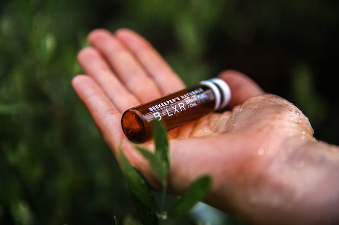 A small brown bottle lies in the palm of a hand amid