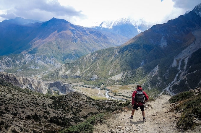 A man in a red hoodie standing on the edge of a cliff at Manang, Nepal