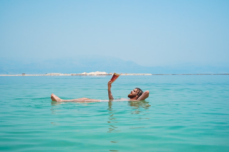 man submerged in the sea reading a book