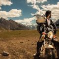 a shot of man on his motorbike looking back at the mountains of pakistan