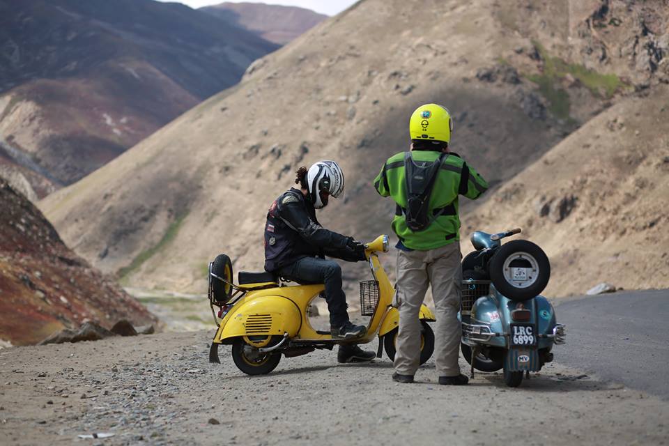 two men on vespas on an open road