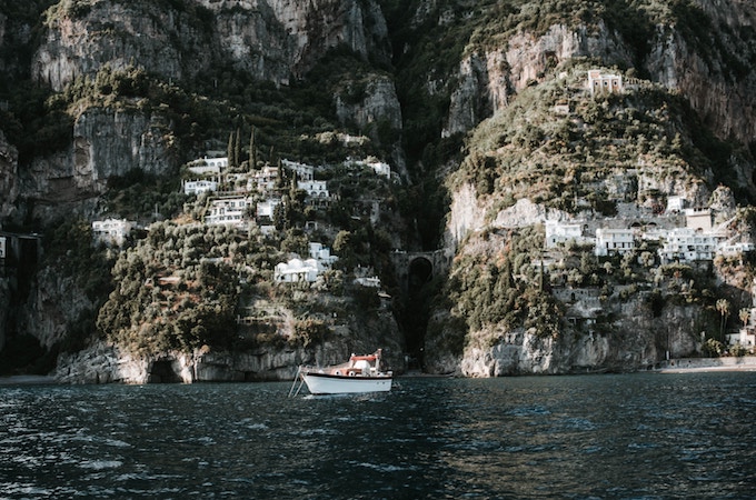 Cliffside buildings and a boat in the sea in Praiano, Italy