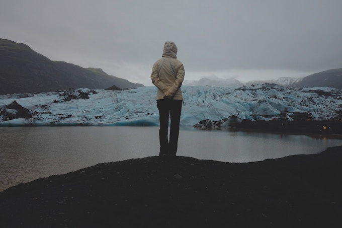 A person with their back to the camera standing in front of a body of water in Iceland