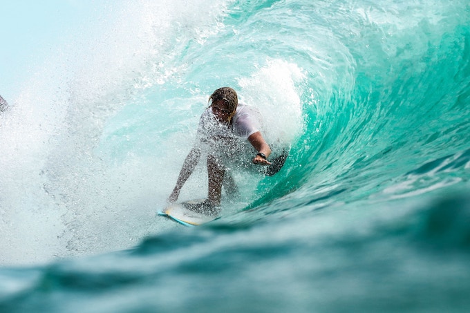 A person surfing a turquoise wave in Bali, Indonesia