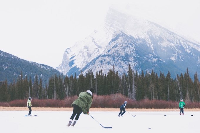 People playing hockey on a frozen lake at the base of a mountain