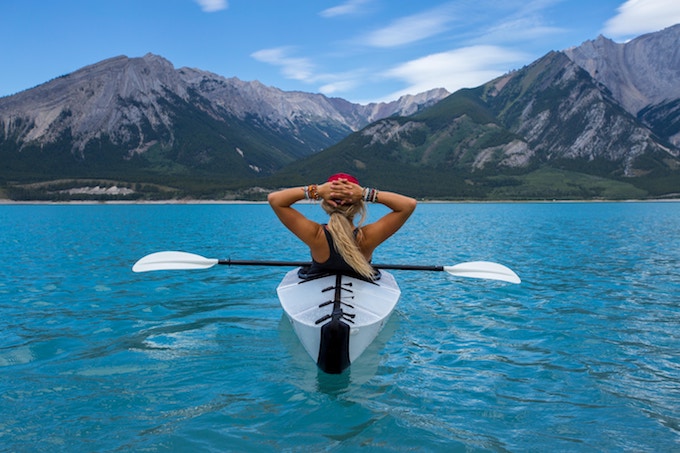 a woman reclining in a kayak on a lake in Canada