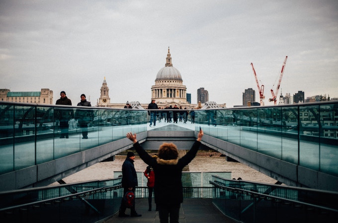 A woman holding both her hands up in front of a building in London, England