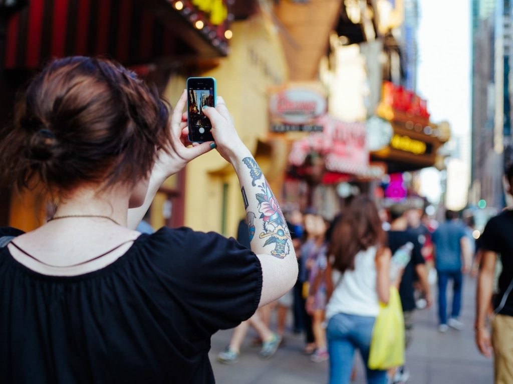 Woman taking a photo with iPhone in Times Square, New York