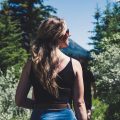 woman wearing black spaghetti strap crop top standing in front of trees while looking left side during daytime