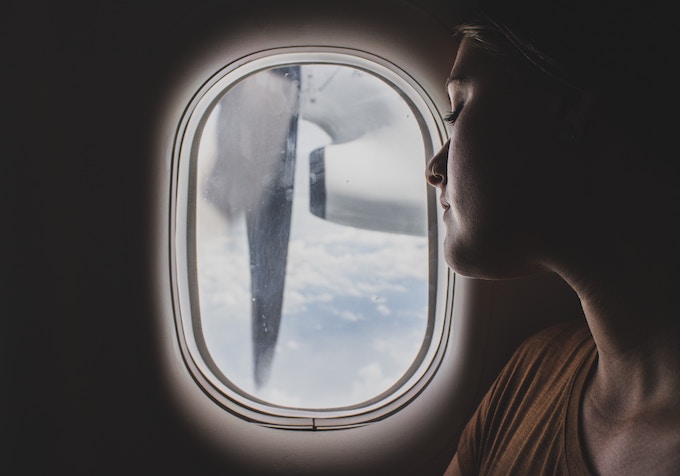 A woman sleeping against the window of a plane