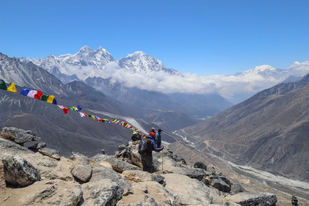 a group of trekkers walking through a valley with fluttering flags in the himalays