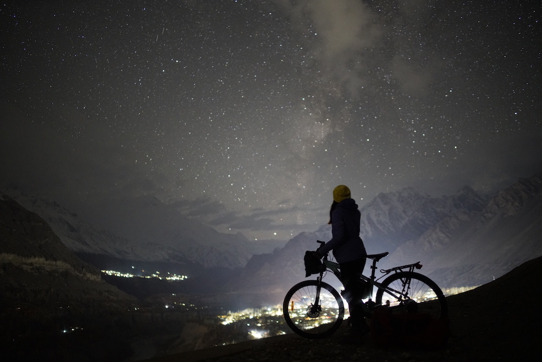 silhouette of a girl with a cycle against a night sky with stars