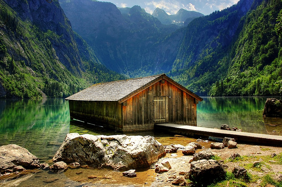 a small wooden hut on the banks of a bay surrounded by scenery