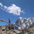 a man standing in a mountain range with colourful flags fluttering in the air