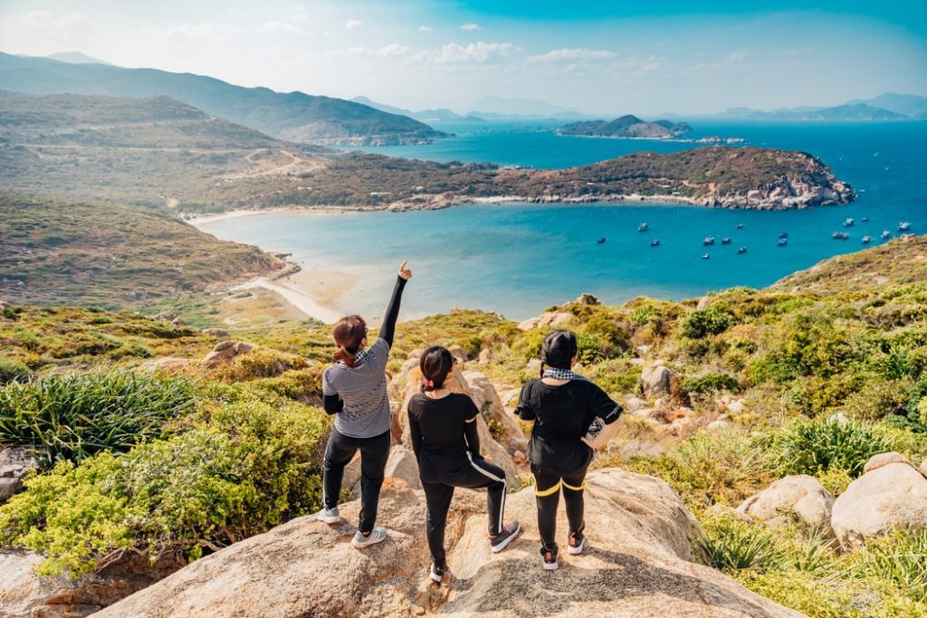 three women standing on a rock overlooking the ocean