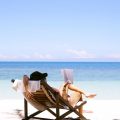 woman sits on brown wooden beach chair in front of the sea