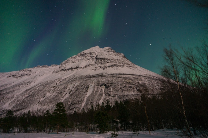 the northern lights over a mountain in norway