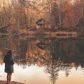 A woman standing in front of a lake in the Falll