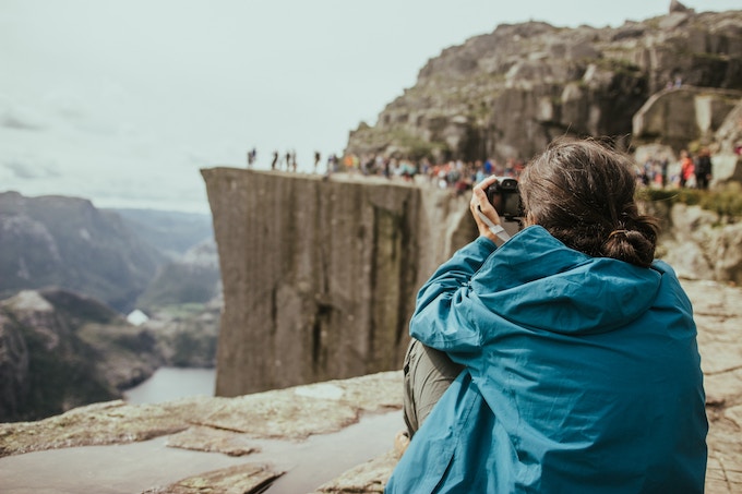 A woman photographing a crowd in Preikestolen, Norway