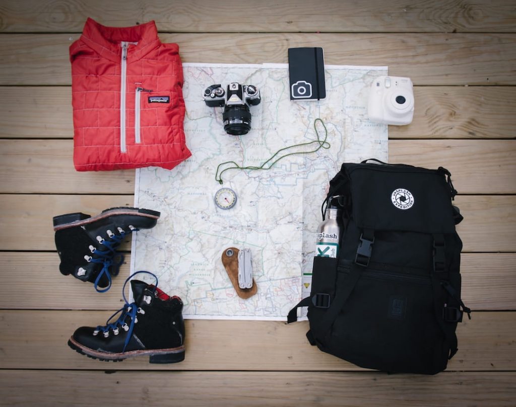 A map and hiking essentials arranged on the floor with a backpack