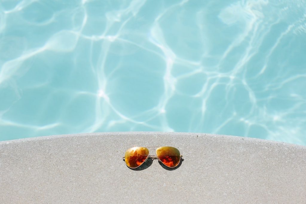 A pair of aviator sunglasses beside a pool