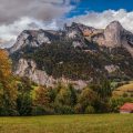 A small hut in front of mountains and trees in autumn